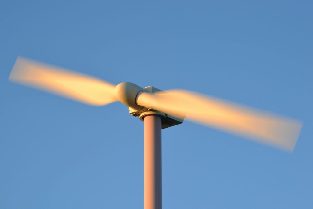 Close-up of a spinning wind turbine against a clear blue sky, symbolizing renewable energy.
